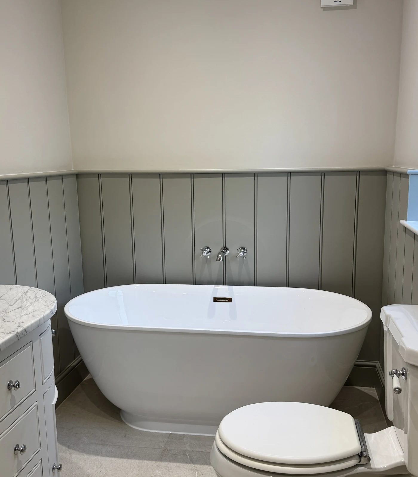 Freestanding bath against sage tongue-and-groove panelling, bathroom renovation Baldock