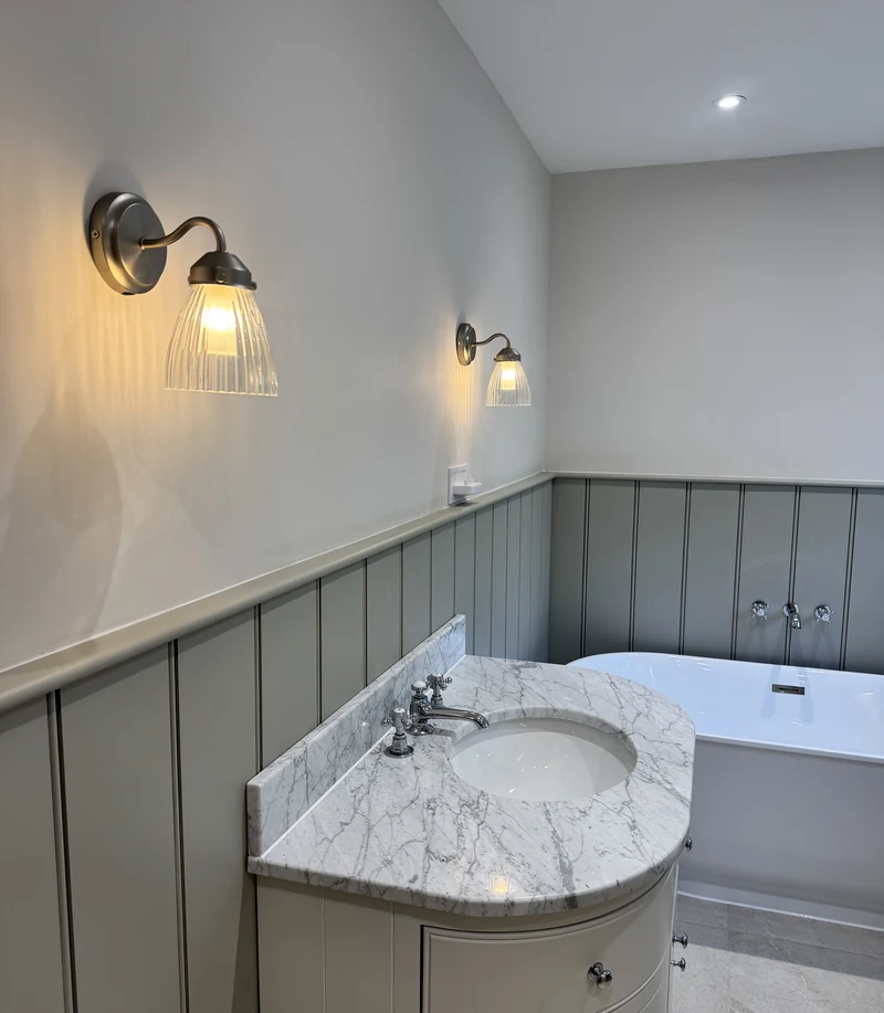Marble-topped vanity and freestanding bath under ribbed wall lights, Baldock