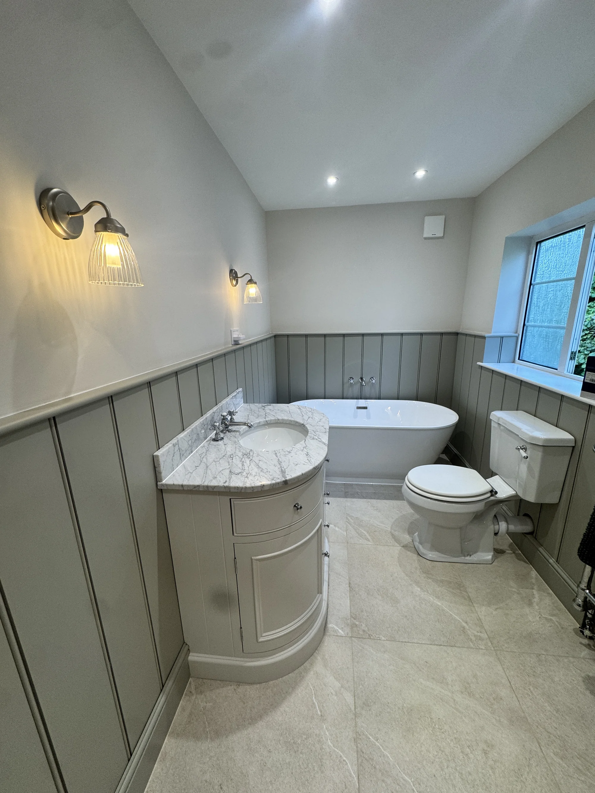 Bathroom renovation with freestanding bath, marble vanity and sage panelling, Baldock