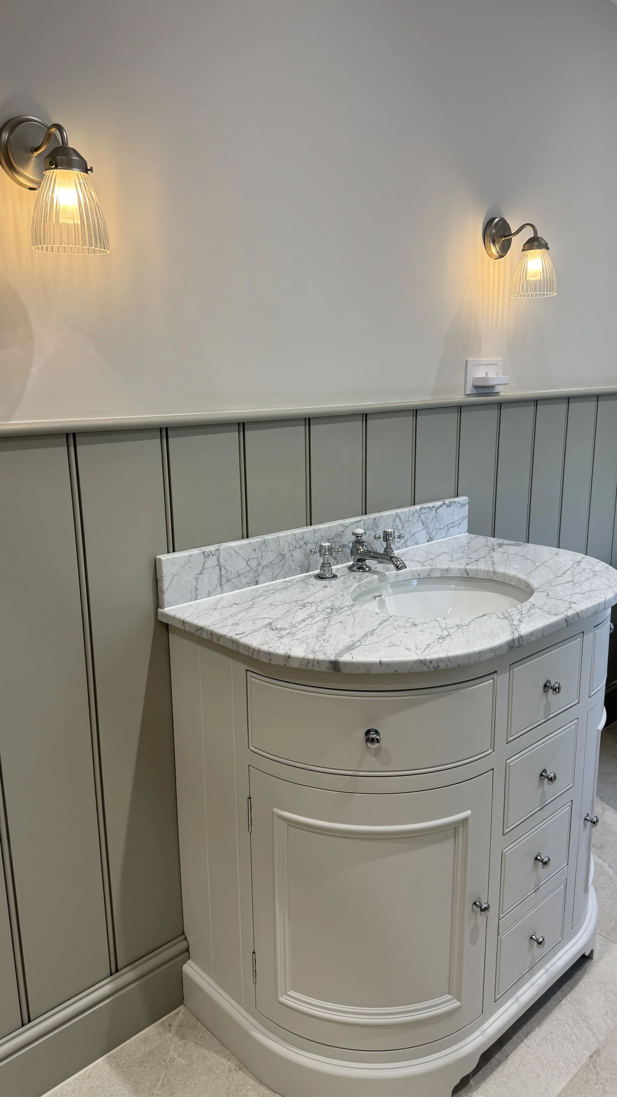 Curved vanity with a marble top and ribbed wall light, Baldock
