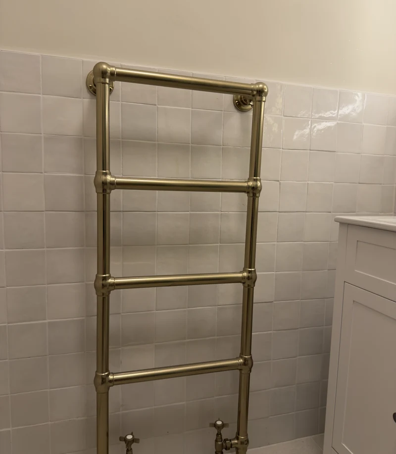 Traditional brass heated towel rail on handmade-look tiling, Hitchin