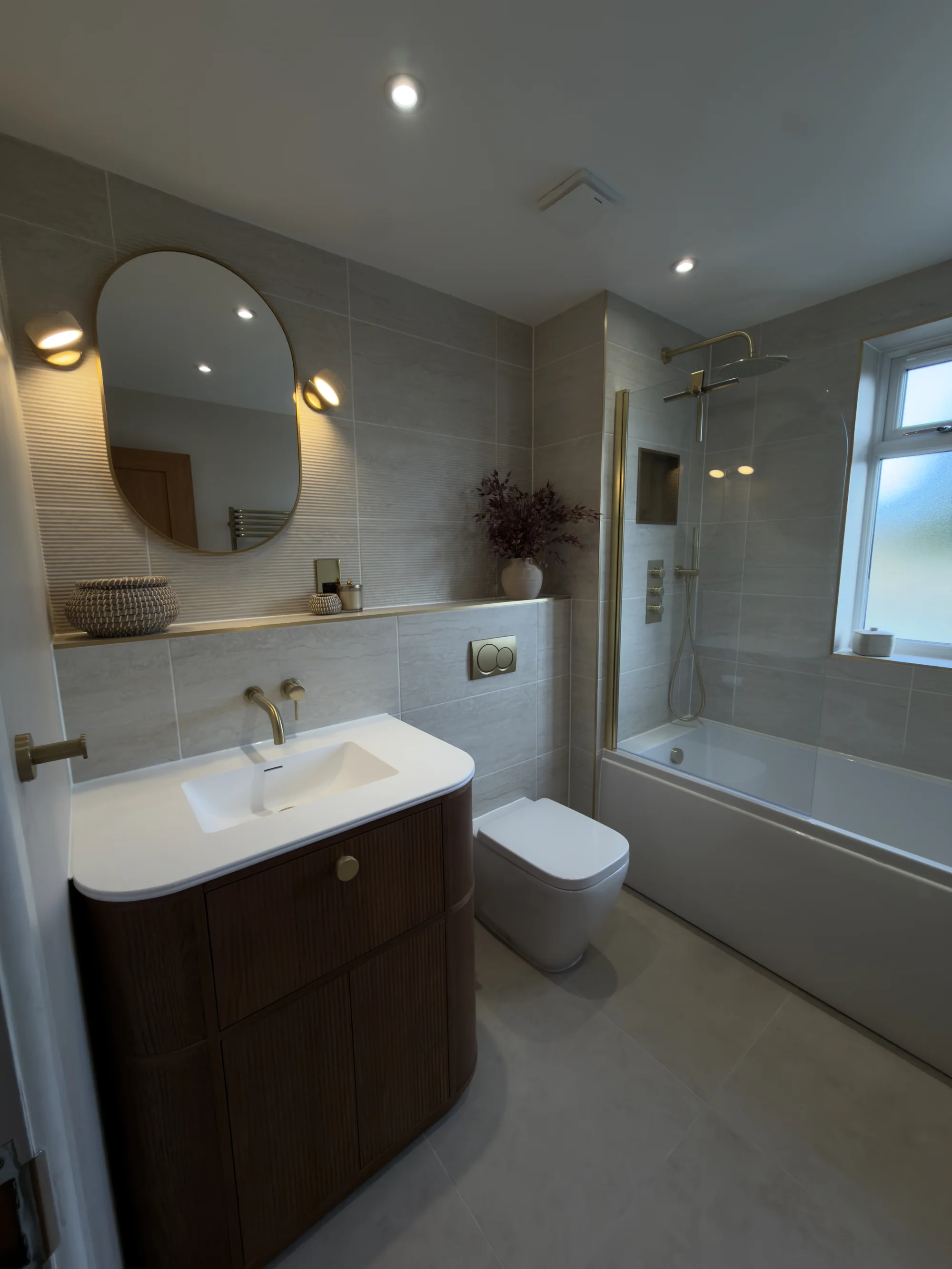 Bathroom renovation with a walnut vanity, oval mirror and stone tiling, Weston