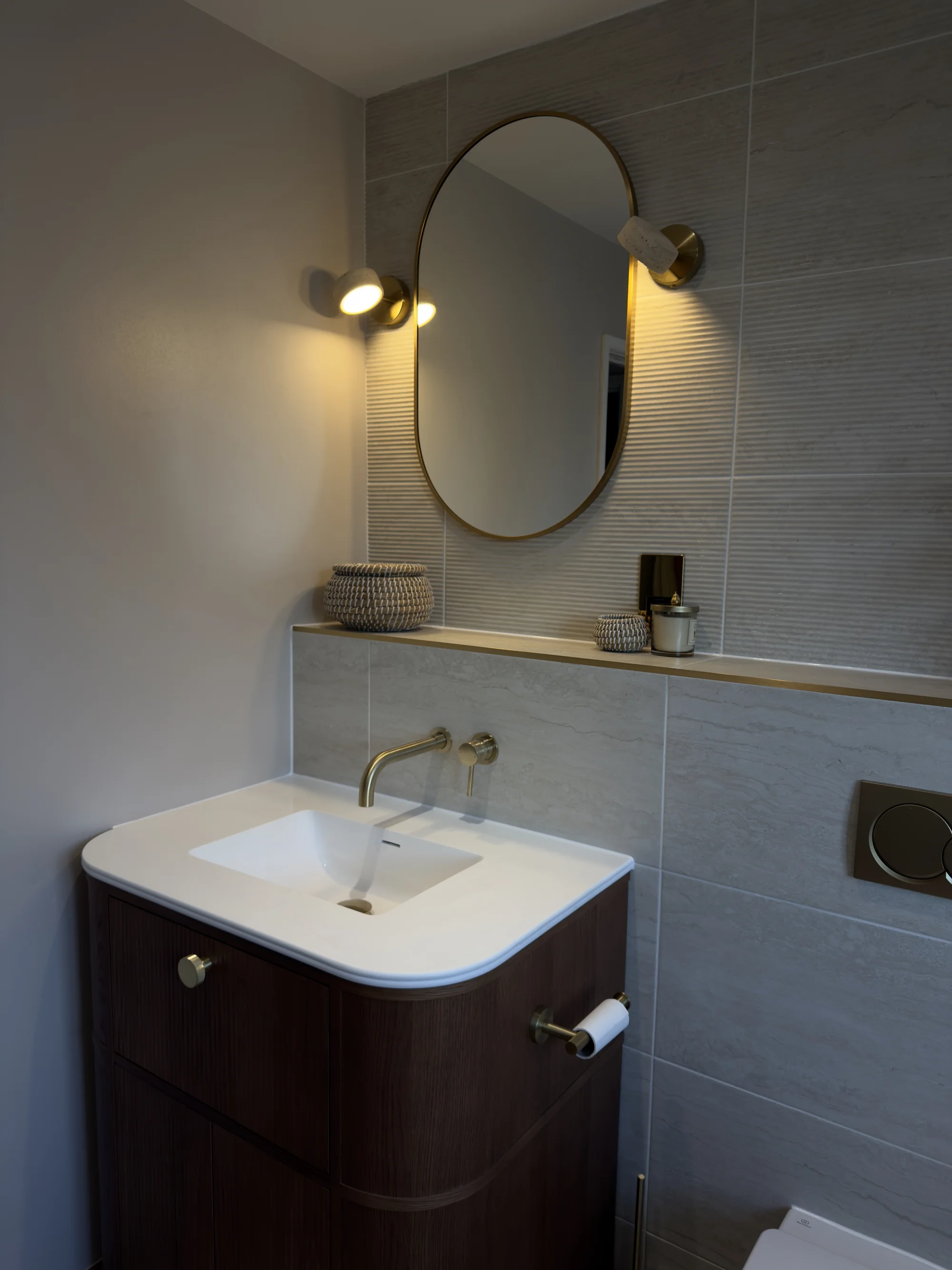 Oval mirror and brass wall lights above the walnut vanity, Weston